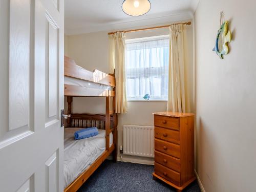 a bedroom with two bunk beds and a window at Leeward Cottage in Wells next the Sea