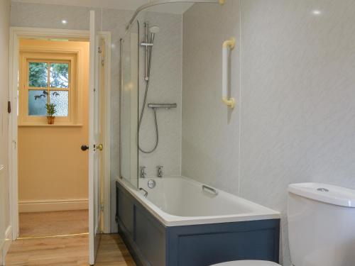 a bathroom with a tub and a shower and a toilet at Laundry Cottage in Rudston
