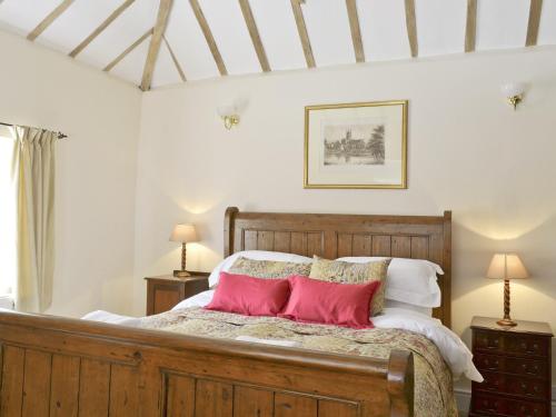 a bedroom with a wooden bed with red pillows at Rose Farm Barn in Laxfield