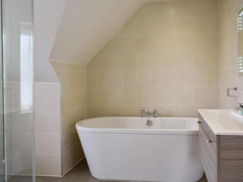 a bathroom with a bath tub and a sink at Grove Cottage in Newchurch