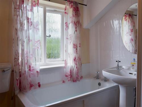 a bathroom with a tub and a sink and a window at The Shippon in Burscough