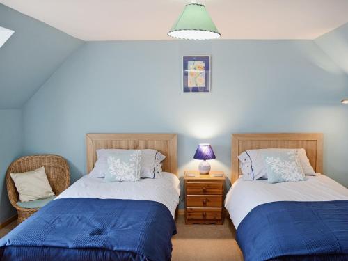 a bedroom with two beds and a lamp on a table at Ben View in Gairloch