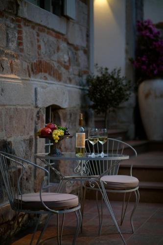a glass table with two chairs and wine glasses at Eressian Hotel & Hammam Spa in Eresos