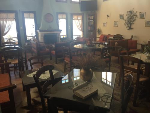 a restaurant with tables and chairs in a room at Iliovolo Guesthouse in Miléai