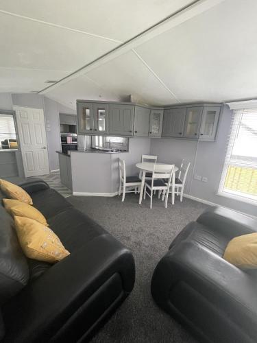 a living room with a black couch and a kitchen at The Winchester Chalet by Sasco in Blackpool
