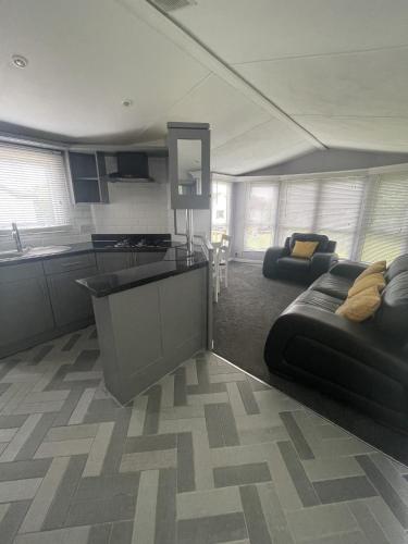 a living room with a black couch and a kitchen at The Winchester Chalet by Sasco in Blackpool