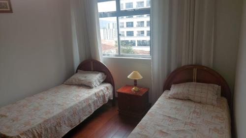two beds in a room with a window at Espaço ALA Minas in São Lourenço