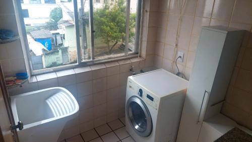 een wasruimte met een wasmachine en een raam bij Espaço ALA Minas in São Lourenço