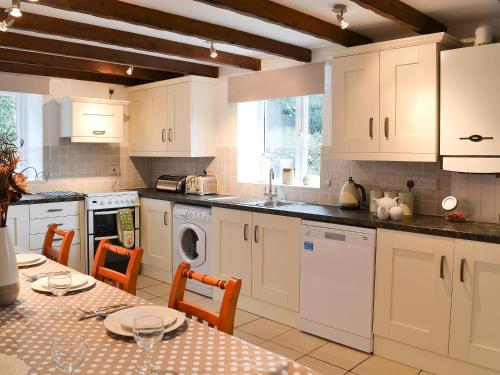 a kitchen with white cabinets and a table with chairs at Bestdale in Frosterley
