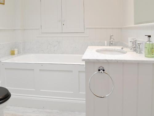 a white bathroom with a sink and a tub at Marsh Barn in Brancaster