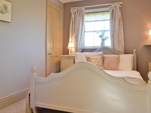 a bedroom with a white bed and a window at 3 Gill Edge Cottages in Countersett