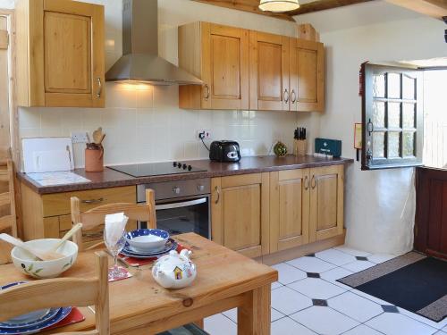 uma cozinha com armários de madeira e uma mesa de madeira em Horseshoe Cottage -31299 em Holywell Bay