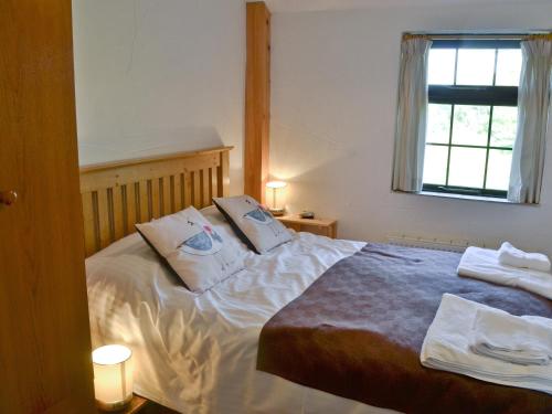 um quarto com uma cama com duas almofadas em Horseshoe Cottage -31299 em Holywell Bay