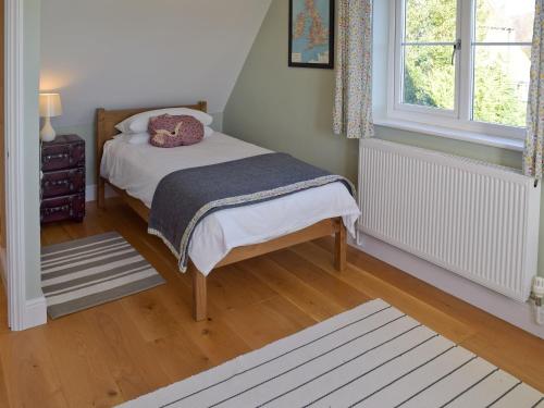a small bedroom with a bed and a window at Granary Cottage in Bentley
