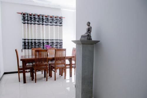 un comedor con mesa, sillas y una estatua en Villa 146 Dickwella, en Batigama
