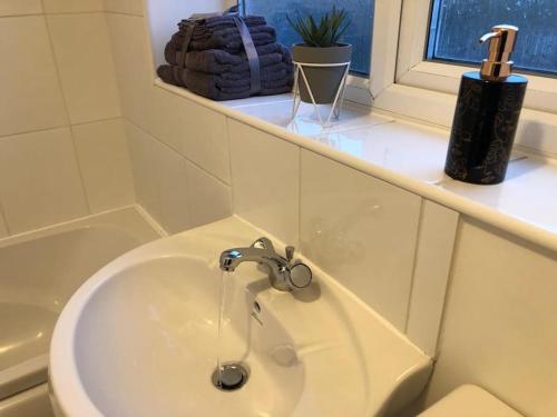 a bathroom sink with a faucet next to a window at Montrose House - Spacious Comfy 3 Bedroom House, Free Wifi and Free Parking in Swindon