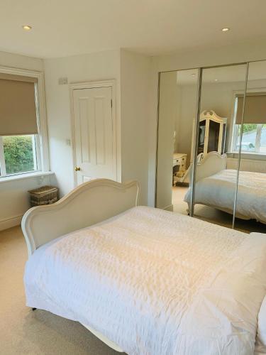 a bedroom with a white bed and a mirror at Elegant 3BD Edwardian Home Warminster in Warminster