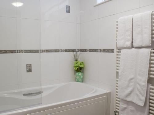uma casa de banho branca com uma banheira e um lavatório em Elm Cottage-w40630 em Gelliwen