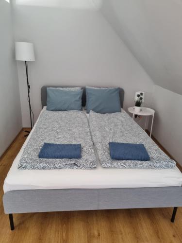 a white bed with two blue pillows on it at Bohém Apartman in Nyergesújfalu