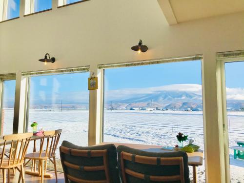 a dining room with a table and chairs and a large window at Shooting Star the Bed & Breakfast in Furano