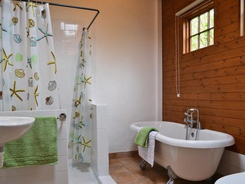 a bathroom with a white tub and a shower curtain at Bwthyn Barri in Sarnau