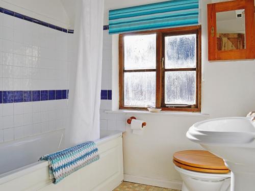 La salle de bains est pourvue de toilettes, d'un lavabo et d'une fenêtre. dans l'établissement Bats Cottage, à Tipton Saint John