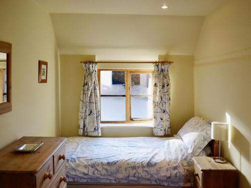 a small bedroom with a bed and a window at Bats Cottage in Tipton Saint John
