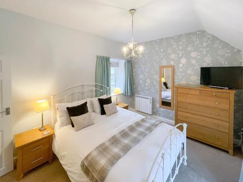 a bedroom with a bed and a dresser and a tv at Riverview Cottage in Hartington