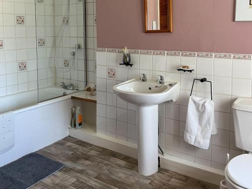 a bathroom with a sink and a tub and a toilet at Commonwealth Cottage in Iron Acton