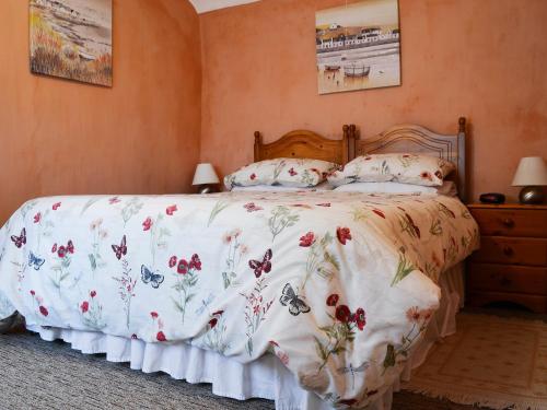 a bedroom with a bed with a floral bedspread at Commonwealth Cottage in Iron Acton
