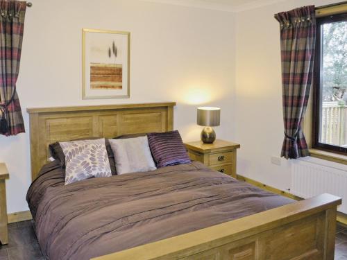 a bedroom with a bed and a lamp on a table at Forest Lodge in Kirkhill