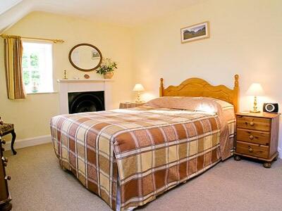 um quarto com uma cama grande e uma lareira em Glencoe Cottage em Glencoe