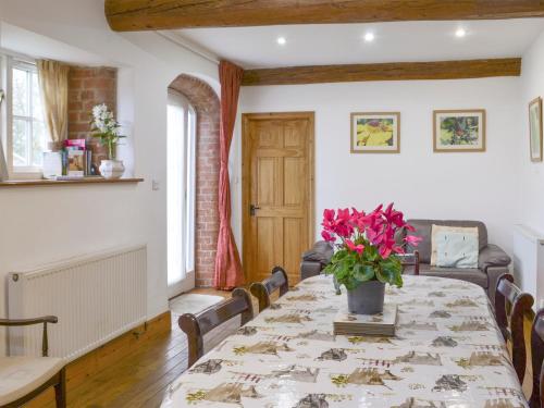 a dining room with a table with flowers on it at The Granary Barn - 25589 in North Willingham