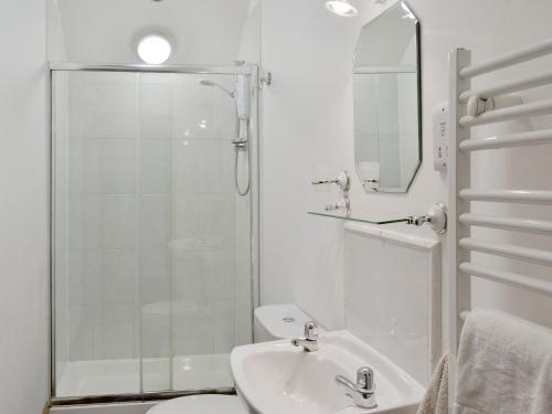 uma casa de banho branca com um chuveiro e um lavatório. em The Granary Barn - 25589 em North Willingham