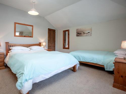 a bedroom with two beds and a mirror at Bowjy Cottage in Cubert
