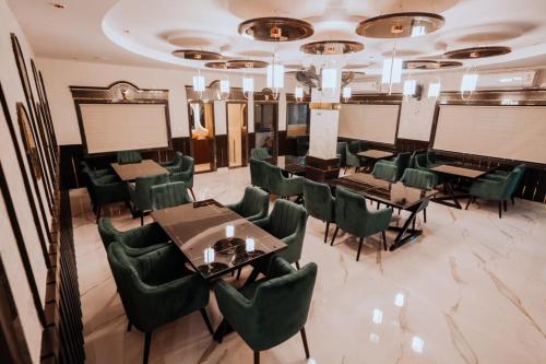 a dining room with tables and green chairs at Bajaj's Karwan Inn in Jagdalpur