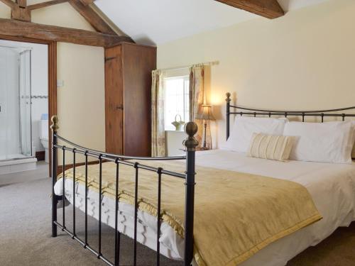 a bedroom with a large bed with a black frame at Burdettes Cottage - 25349 in Findern