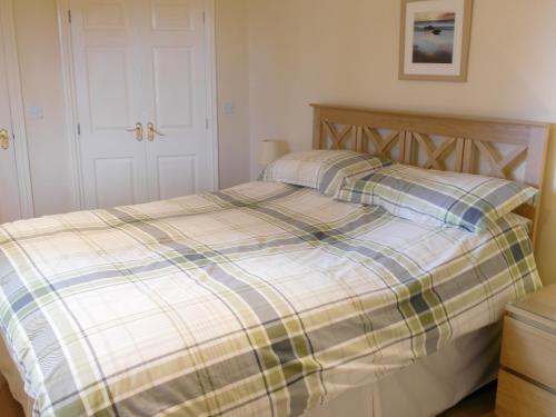 a bedroom with a bed with a plaid blanket at Woodpeckers Cabin in Bridlington