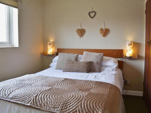 a bedroom with a large bed with two pillows at Pine Cottage in Cote