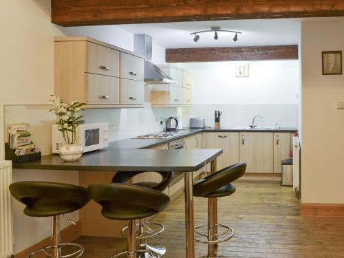 a kitchen with a table with chairs and a microwave at The Hay Barn- 26724 in North Willingham