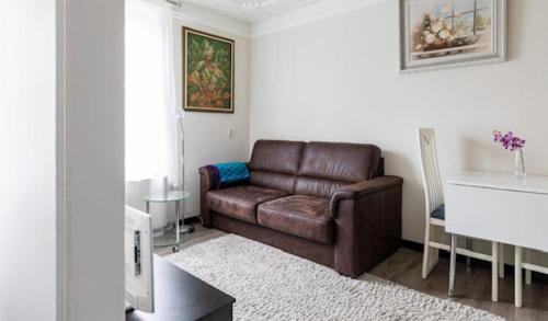 uma sala de estar com um sofá de couro castanho e uma mesa em Onder de molen em Hollum