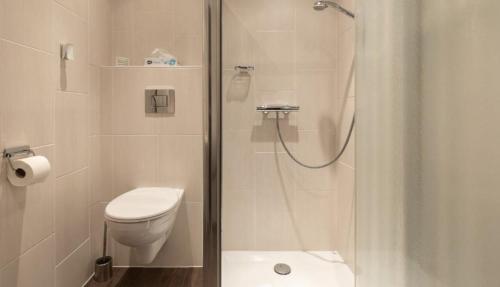 uma casa de banho branca com um chuveiro e um WC. em Onder de molen em Hollum