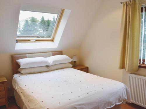 a bedroom with a white bed with a window at Lime Tree Cottage in Oakley