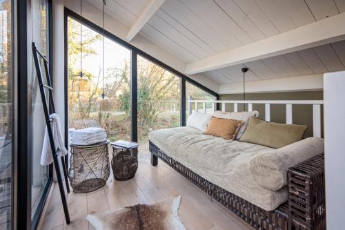 eine abgeschirmte Veranda mit einem Bett und einem Fenster in der Unterkunft Marie à la Campagne in Dolembreux