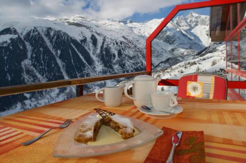 a plate of food on a table with mountains in the background at Hotel Bellwald in Bellwald