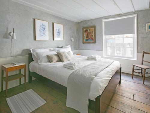 a bedroom with a large white bed with a window at Smugglers Cottage in Margate