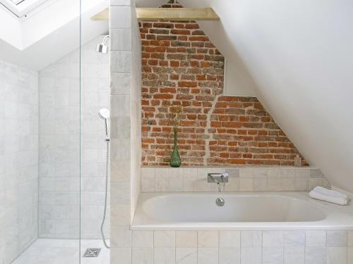 a bathroom with a bath tub next to a brick wall at Smugglers Cottage in Margate