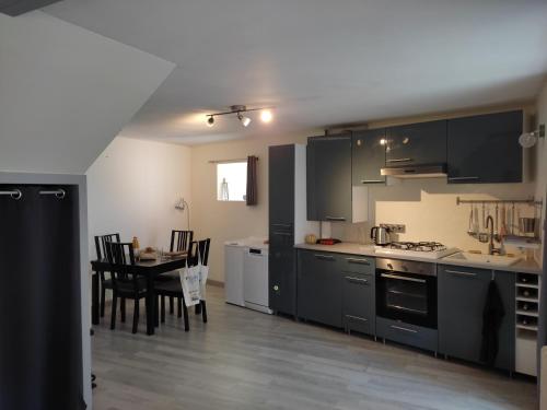 Una cocina con gabinetes negros y una mesa y sillas. en La Maison du Verger avec Jardin, en Carnac