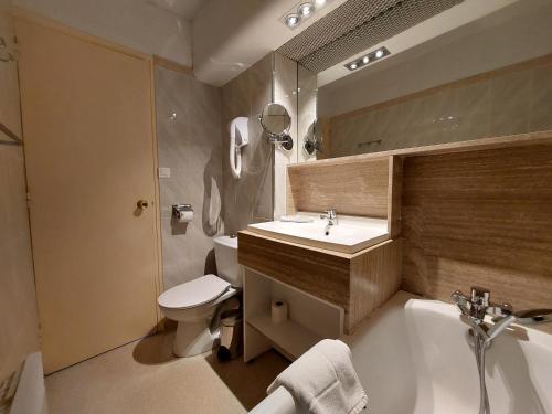 a bathroom with a sink and a toilet and a tub at Hôtel-Résidence Le Lys in Cauterets
