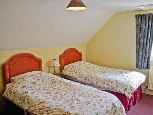 Shipton MoyneにあるWestonbirt Cottageのベッドルーム(ベッド2台、ランプ付)